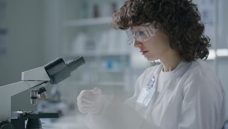 female scientist pipetting liquid onto slide and examining under microscope