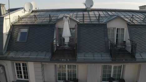 Wedding-gown-dress-hanging-at-balcony-terrace-doorway-waits-for-bride-at-sunny-morning,-aerial-view