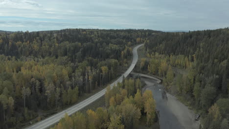 scenic view of a remote road over river among lush spruce trees in british columbia, canada