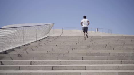 vista trasera de un hombre afroamericano corriendo por las escaleras