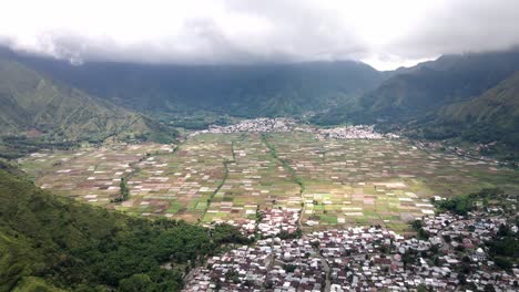 epic drone shot of the valley and sembalun village agriculture land with volcano mountain range at the background near volcano rijani national park, lombok, indonesia