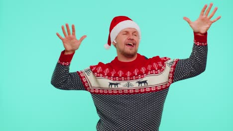 Man-in-Christmas-sweater-listening-music-via-earphones,-dancing-disco-fooling-around-having-fun