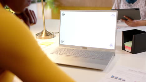 African-american-casual-businesswoman-using-laptop-with-copy-space-on-screen-in-office,-slow-motion