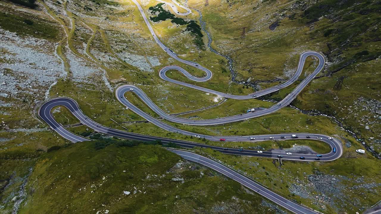 Drone-zoom ud fra stor højde, der afslører snoede bjergveje nedenfor.