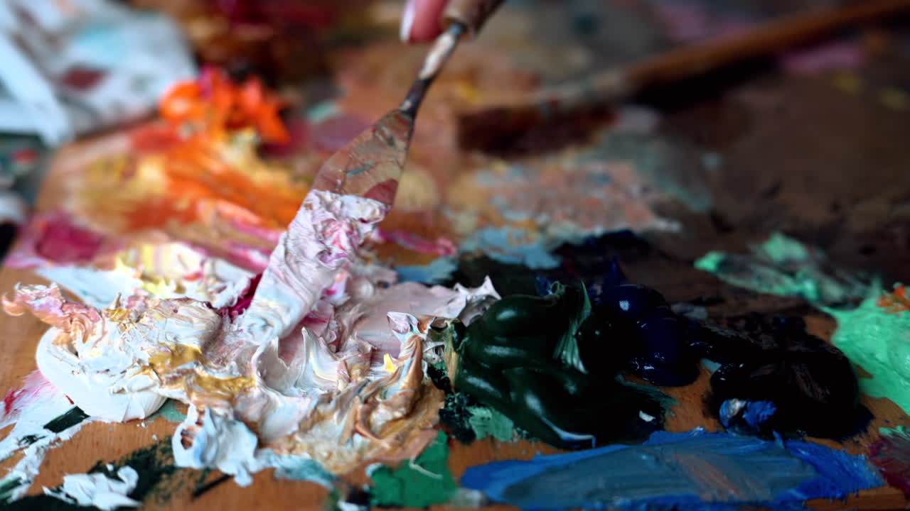 Close up of a woman picking up paint from a palette