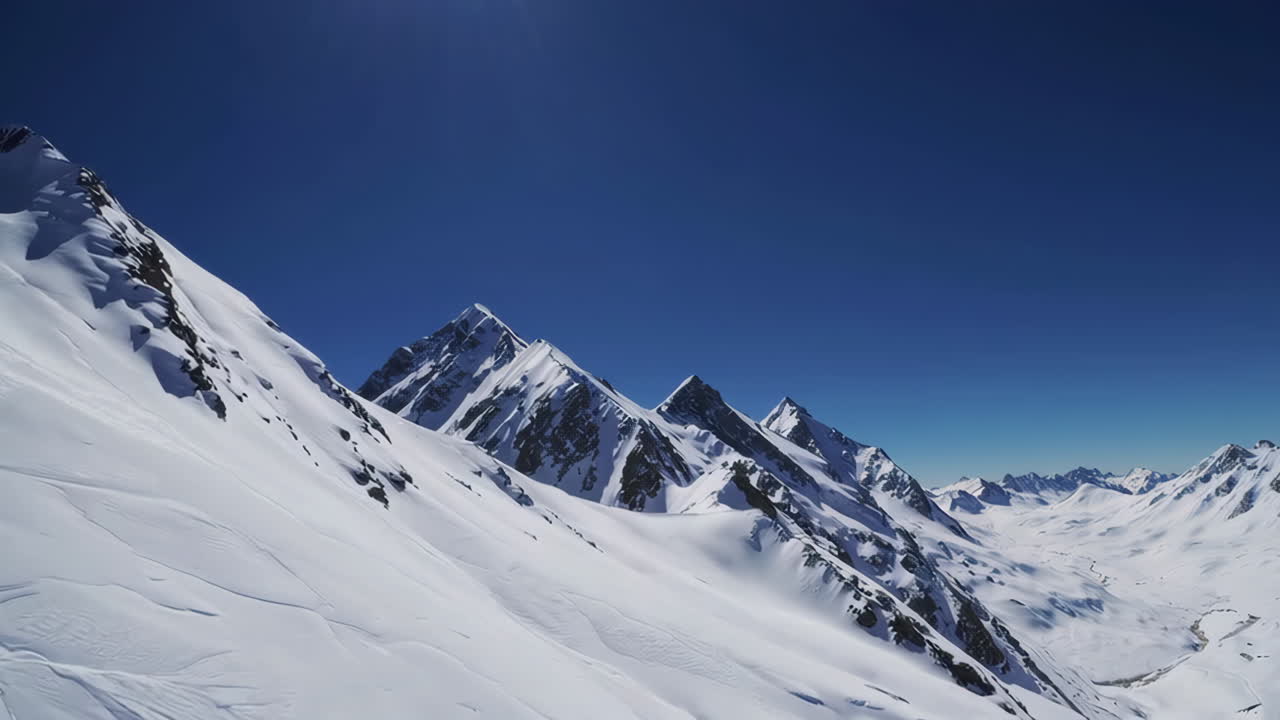Panoramic View of Snow-Covered Mountains Under a Clear Blue Sky