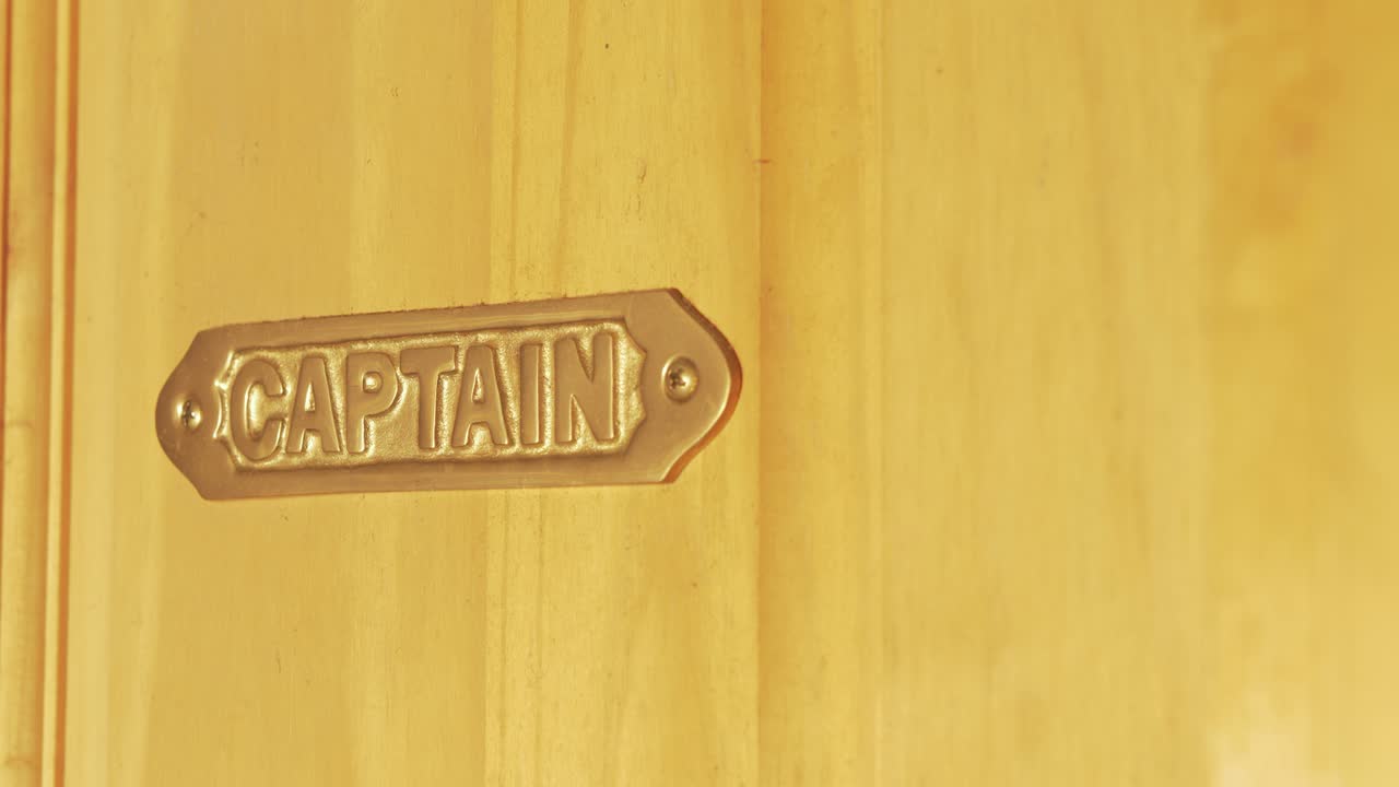 el capitán de metal de latón canta montado en una puerta de madera.