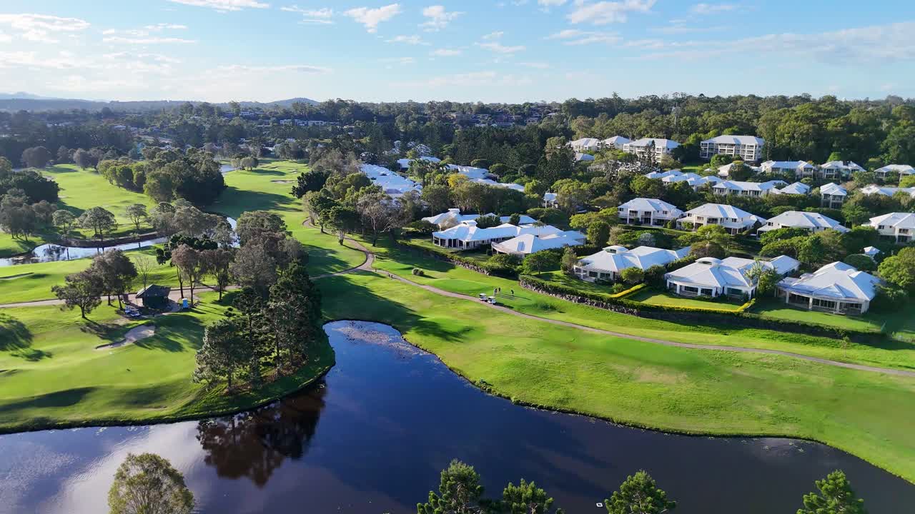 Drone footage captures a serene golf course and resort in Gold Coast, Australia, under clear skies with lush greenery and water features