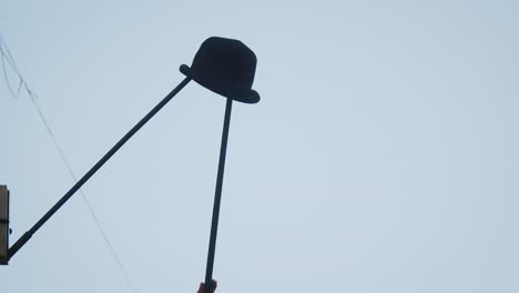 Bowler-hat-hanging-on-pole-being-taken-down-by-the-busker-artist-during-street-exhibition