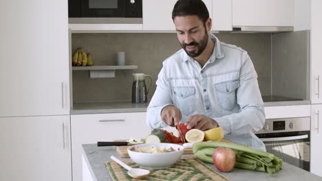 joven feliz cocinando ensalada