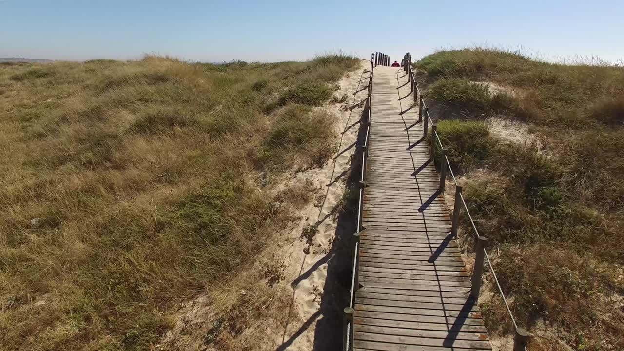 volando sobre la pasarela en dirección a la playa sobre las dunas