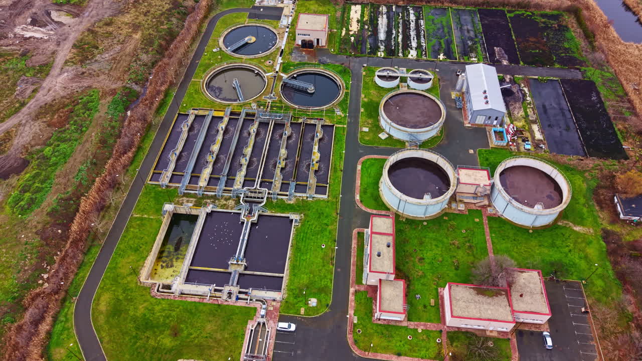Wastewater treatment facility in a rural area with multiple tanks and processing units surrounded by green land and roads