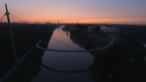 aerial view of suspension bridge above the river during sunset