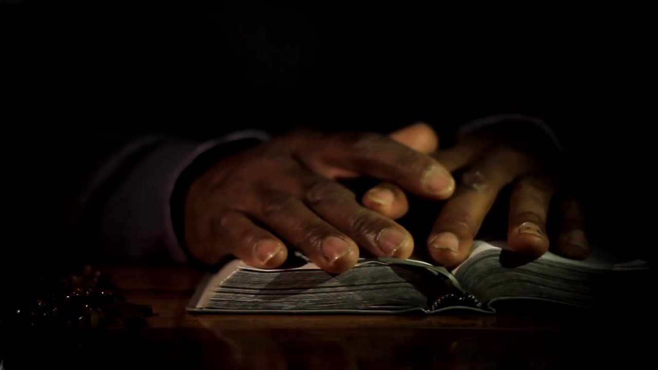 Vidéo de stock : un homme caribéen priant Dieu, les mains jointes, avec une bible, sur fond blanc