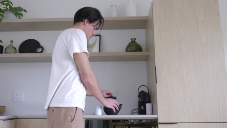 young man pours tea powder into teapot, making tea in the morning at the hotel room