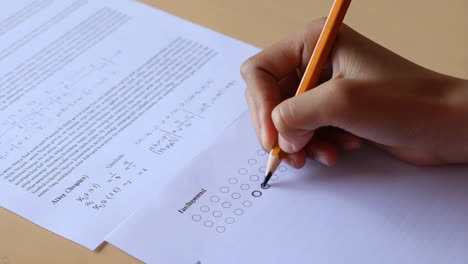 student's hand marking answers on a test paper