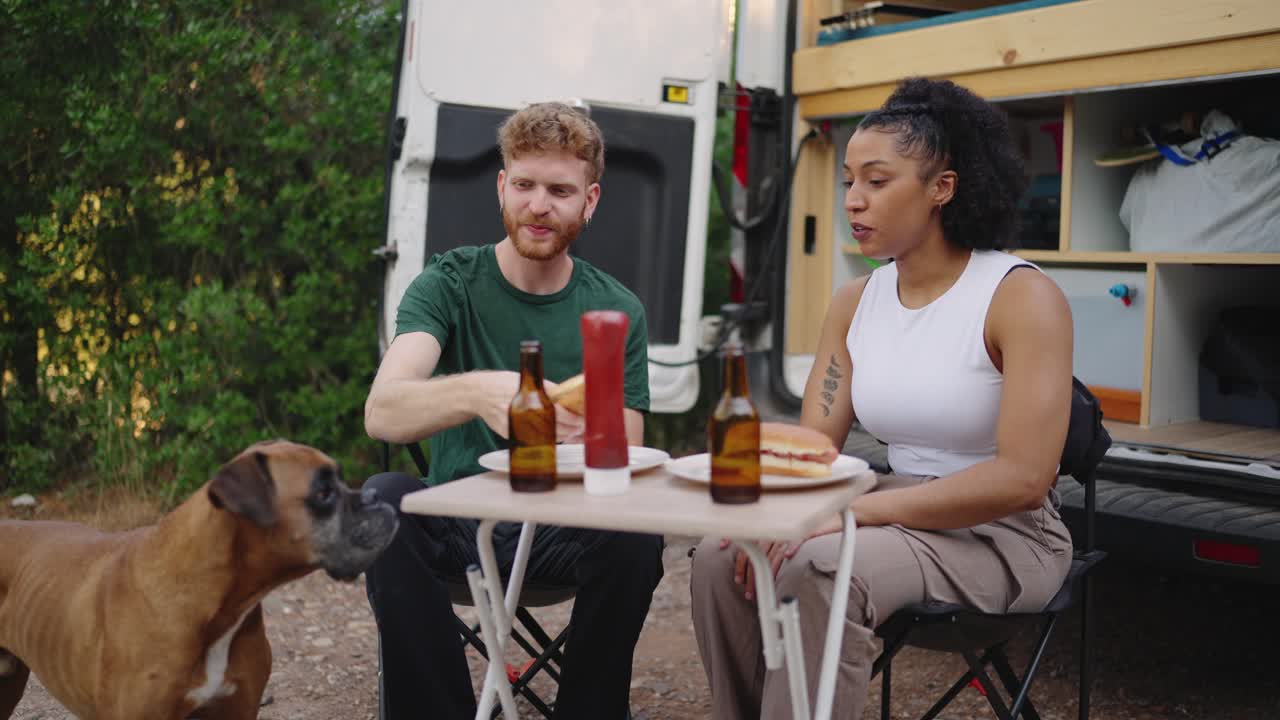 Couple enjoying a meal outdoor with their dog during a vanlife road trip