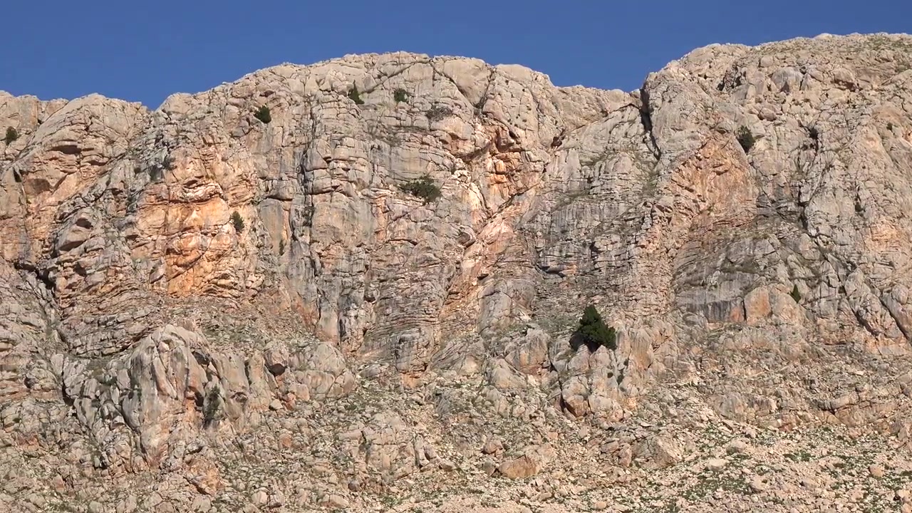 Parete rocciosa di montagna aspra sotto un cielo azzurro e limpido