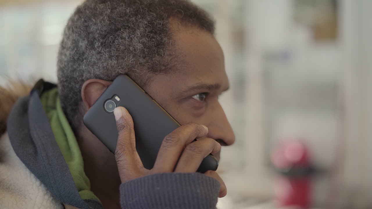 African American man talking by smartphone in cafe
