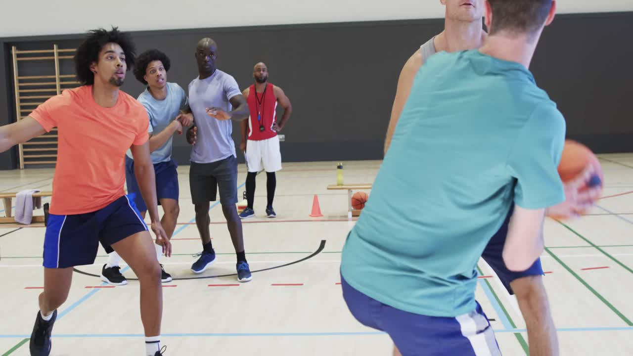 다양한 남성 농구 선수들이 실내 코트에서 경기 중에 공을 드리블하고  ⁇ 고 있습니다.