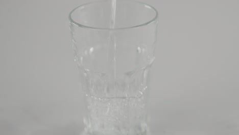 Stilles-Wasser-In-Zeitlupe,-Das-Vor-Neutralem-Hintergrund-In-Klares-Glas-Strömt