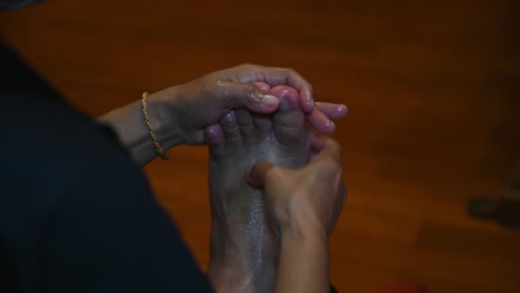 left hand holding the foot from moving while the right hand works with pressure relaxing ones foot, foot and thai massage or nuat phaen thai, thailand