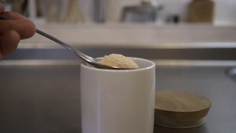 Toma-En-Cámara-Lenta-De-Una-Cucharada-De-Azúcar-Sacada-Del-Recipiente-En-Una-Cocina