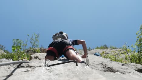 man climbing up mountain looking up, shot from below