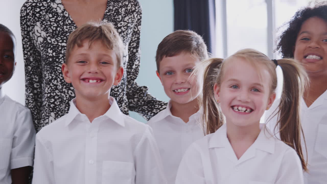 портрет учеников начальной школы в униформе в классе с учителем-мужчиной