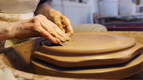 Primer-Plano-De-Un-Alfarero-Masculino-Poniendo-Diseño-En-Placa-De-Arcilla-En-Un-Torno-De-Alfarería-En-Un-Estudio-De-Cerámica