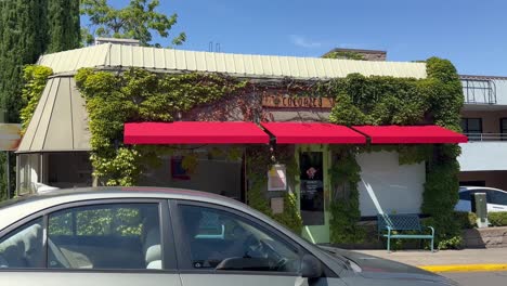 restaurant storefront with red awnings and greenery along street in ashland, oregon. static shot