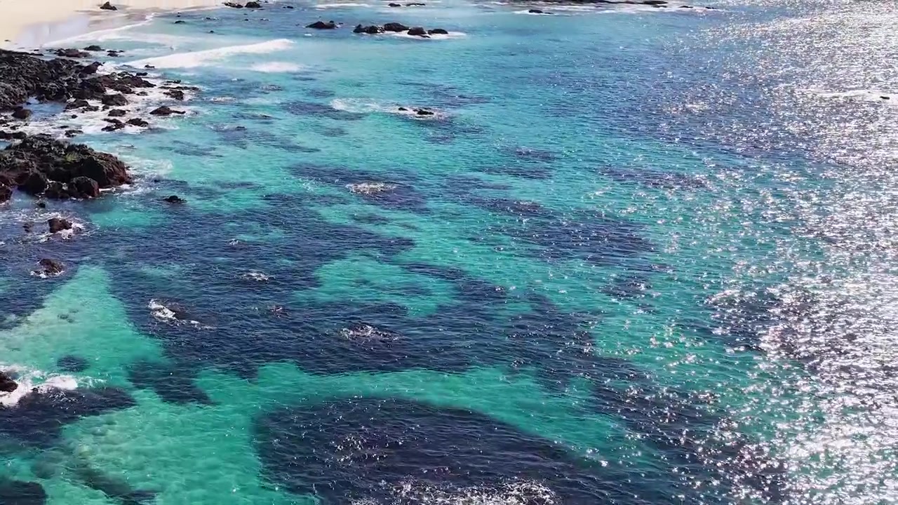 Luchtbeeld van de turquoise golven van de oceaan die op de rotsachtige kustlijn botsen