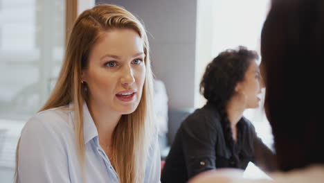 young businesswomen meeting around table having discussion in modern workspace