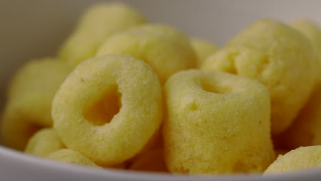 close up snack food crispy corn rings chips salty rotates slowly. fast food or junk food snacks unhealthy concept.