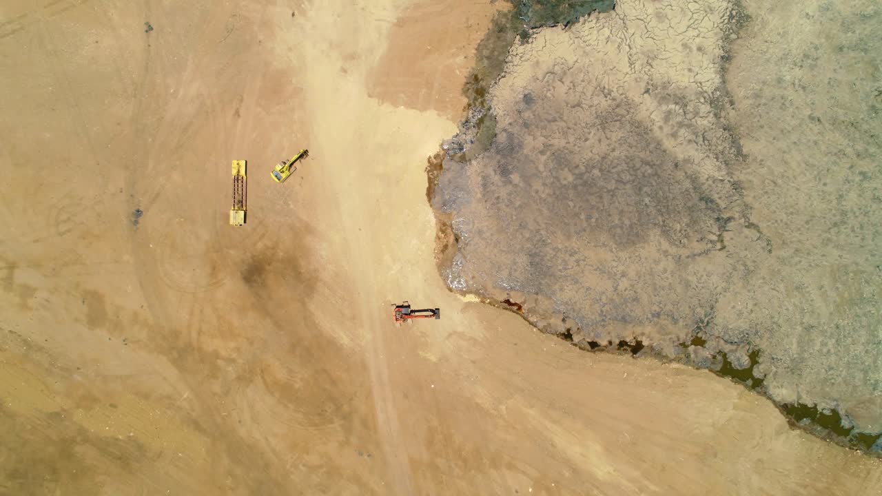Aerial bird's eye view rising above sandy pit with excavator and loader