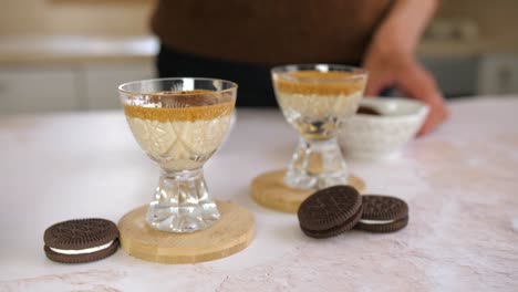 woman sprinkling cocoa crumbs on dalgona coffe with spoon, closeup