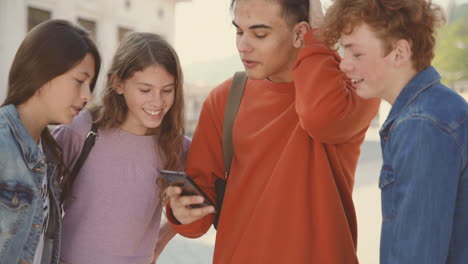 a group of teenagers with two girls and two boys watching something on the screen of a mobile phone 2