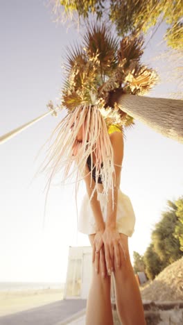 woman with braids posing under a palm tree