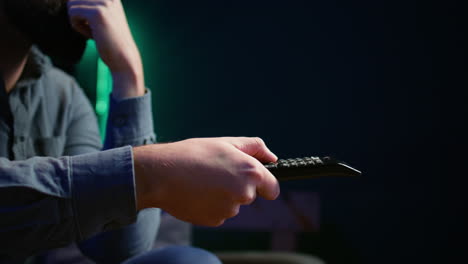 close up of man on couch using remote control