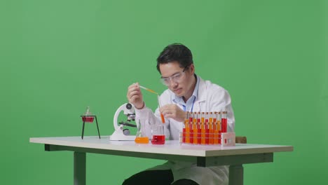 Side View Of Asian Man Scientist Making Experiment With Test Tube And Screaming Goal Celebrating While Working On The Table With Microscope In The Green Screen Background Laboratory