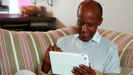 Älterer-Mann-Mit-Digitalem-Tablet-Zu-Hause-Im-Wohnzimmer