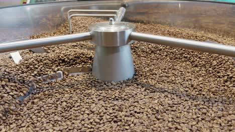 observe the intricate process of roasting coffee beans in an industrial setting.