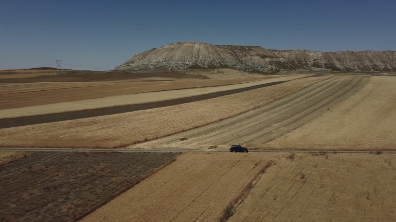 마른 농작물 땅에서 멀리 떨어진 측면에서 suv를 따라 공중 촬영