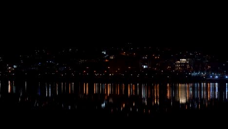 City-lights-reflecting-on-lake-surface-at-night,-beautiful-cityscape-with-colorful-spotlights-in-Tirana