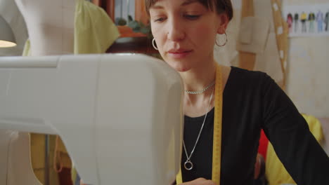 seamstress using sewing machine at work in dressmaking studio