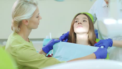 dentista con asistente preparándose para el tratamiento dental. paciente en la silla del dentista