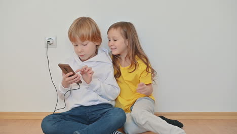 little boy and girl with a smartphone using an app and playing an online video game