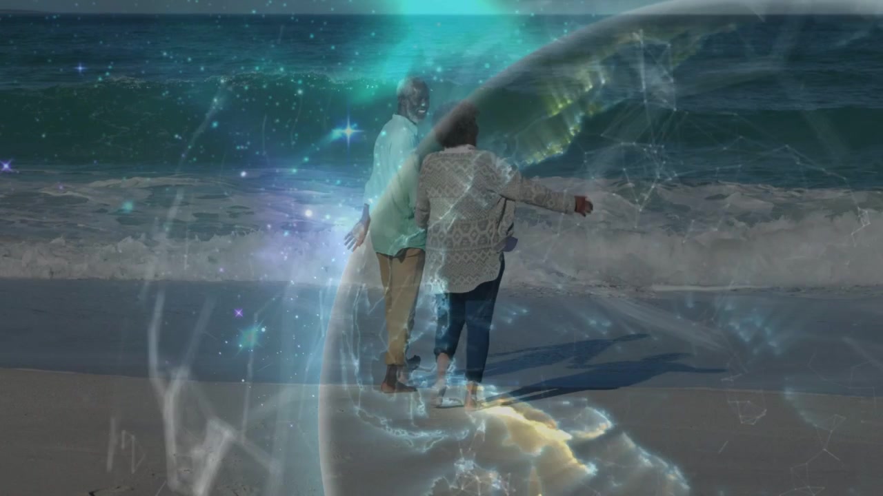 Couple walking beach, linking, steadying while globe overlay sweeping in over them showing travel