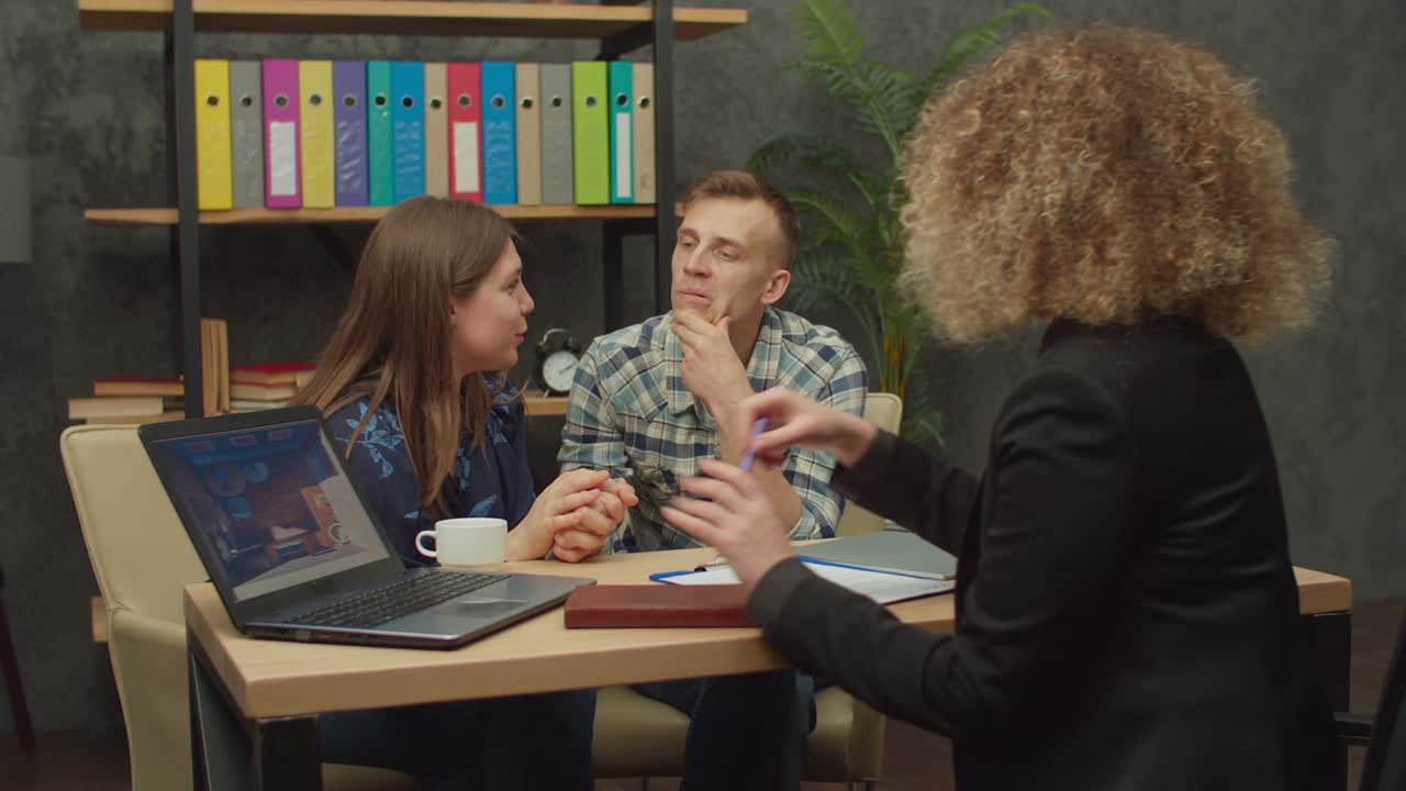 una mujer encantadora persuadiendo a un marido obstinado para que compre una casa nueva en la oficina de un agente inmobiliario.