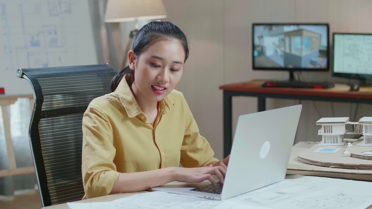 Asian Woman Engineer Typing On A Laptop At The Architectural Office